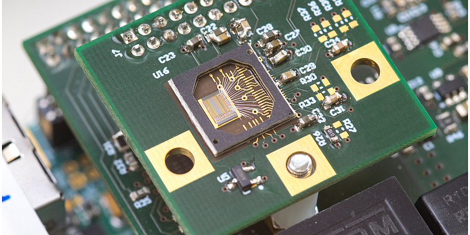 Eine grüne Platte mit mehreren goldenen Plättchen. In der Mitte ein Sensor.