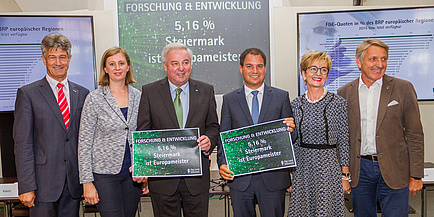 VertreterInnen aus Politik, Wirtschaft und Wissenschaft präsentieren anhand von Tafeln die Forschungsquote der Steiermark.