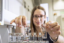 Eine Frau sortiert Glasfläschchen auf einem Laborteller.