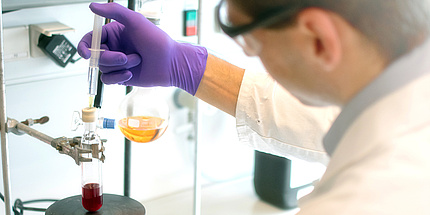 Researcher with syringe and flask