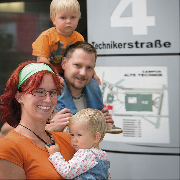 Eine Frau und ein Mann mit zwei Kindern vor einer Infotafel der Technikerstraße. Bildquelle: Lunghammer – TU Graz