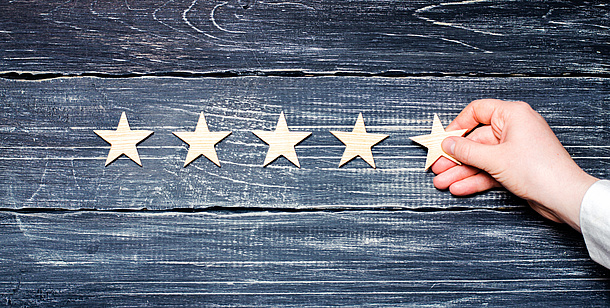 A hand places a star next to four more stars.