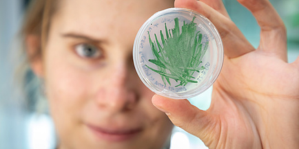 Woman with petri dish and green algae inside