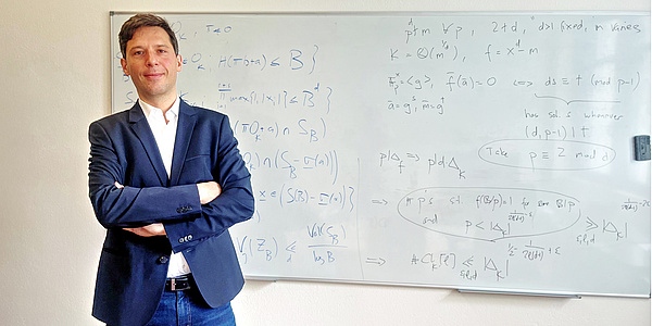 Martin Widmer steht mit verschränkten Händen vor seinem vollgeschriebenen Whiteboard.