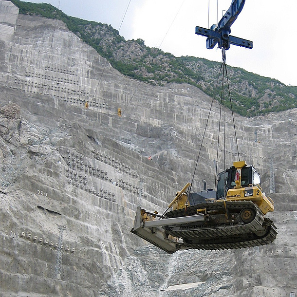 Construction machine is moved by crane at Deriner Damm as a symbol for the learning contents of the master study Geotechnical and Hydraulic Engineering at TU Graz