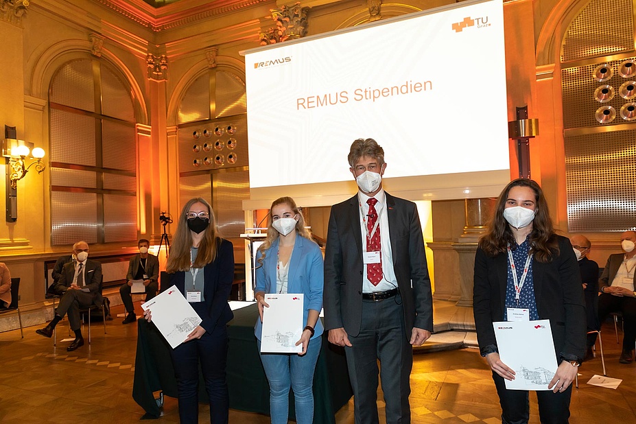 Three students with certificates and Rector Harald Kainz