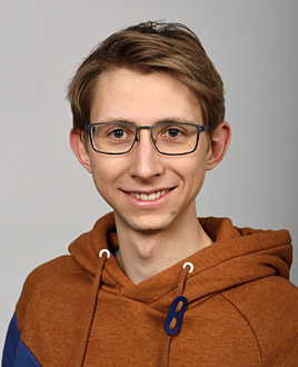A man with glasses smiles into the camera
