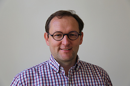 Portrait of a TU Graz researcher with glasses and checked shirt