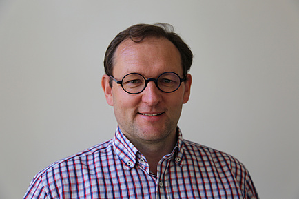 Porträt eines TU Graz-Forschers mit Brille und kariertem Hemd