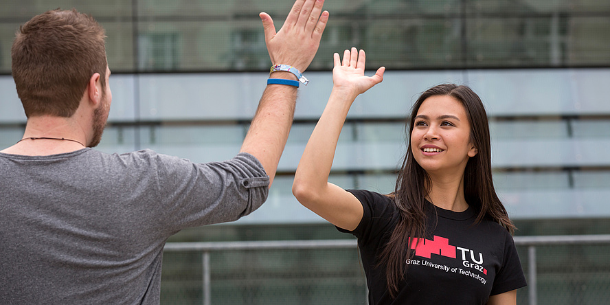 Eine Studentin und ein Student der TU Graz klatschen die Hände zusammen.
