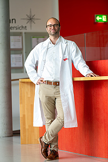 Smiling man with glasses and lab coat.