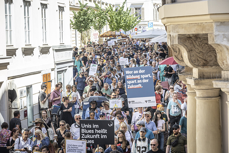 A large crowd is jostling its way through a narrow alley.