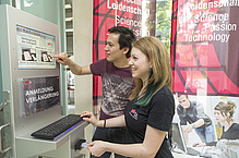 Young man and young woman in front of an information terminal.