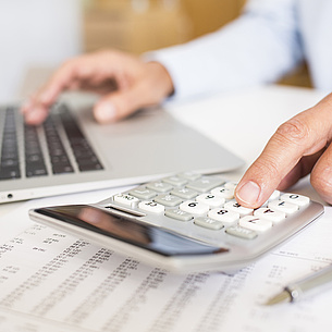 Hands operating a calculator and a laptop at the same time. Photo source: Idprod - fotolia.com