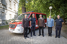 Fünf Männer stehen vor einem Feuerwehrauto. 