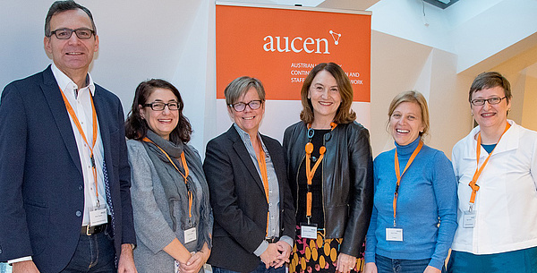 6 people in front of an "aucen" roll up banner. Source: AUCEN