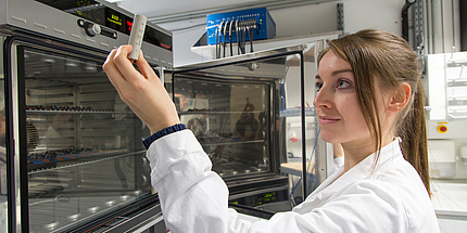 Woman looks at battery in her hand 