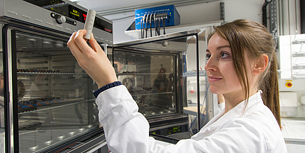 Woman looks at battery in her hand 