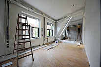 Room under construction with electricians working in the background.