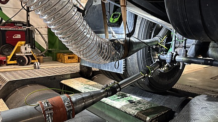 Photo of the underside of a car currently on a test bench. Hoses and pipes lead from the brake of a tyre to the side of the image.