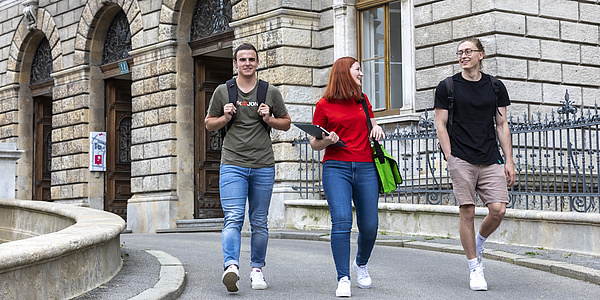 Drei Studierende vor dem Eingang zur TU Graz
