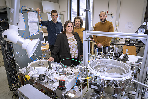 Two women and two men stand behind a table with technical apparatus.