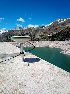An antenna on a dam wall above a reservoir