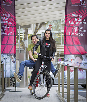 Zwei Studierende auf einem Fahrrad