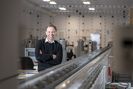 A man stands in a laboratory and smiles into the camera