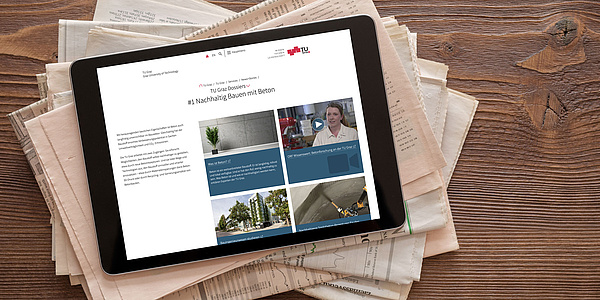 Zeitungsstapel, darauf ein Tablet mit der Ansicht der Seite "TU Graz Dossiers".