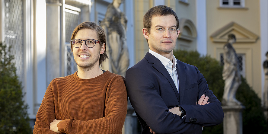 Two men stand side by side looking at the camera.