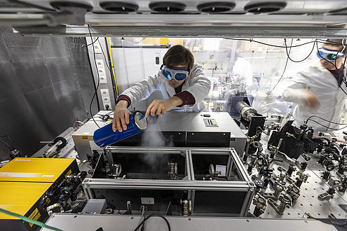 A man wearing safety goggles leans over a machine and lets the vapour of dry ice flow out of a container.