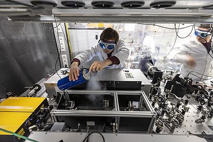 Ein Mann mit Schutzbrille beugt sich über eine Maschine und lässt den Dampf von Trockeneis aus einem Gefäß strömen.