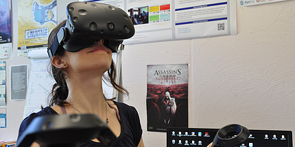 A young woman is wearing a large black VR headset.