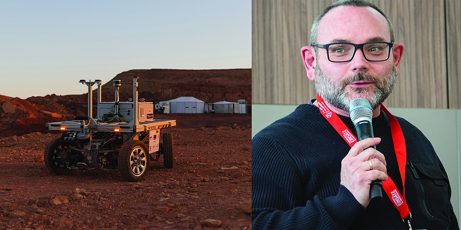 A four-wheeled robot stands in the desert. On the right, a man speaks into a microphone.