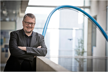 TU Graz researcher with crossed arms and glasses