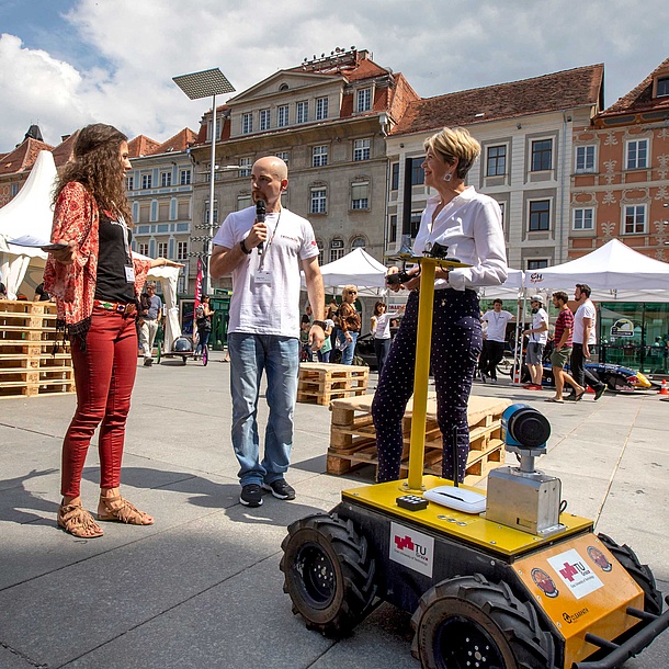 A researcher shows a robot to visitors.