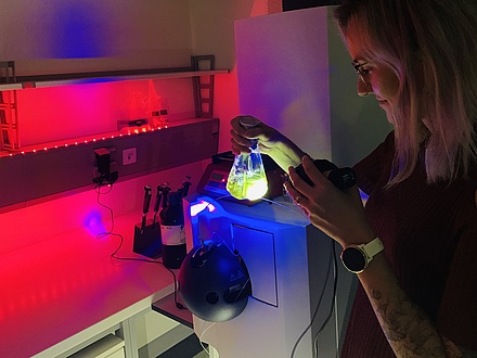 A woman in a laboratory holds an illuminated glass container