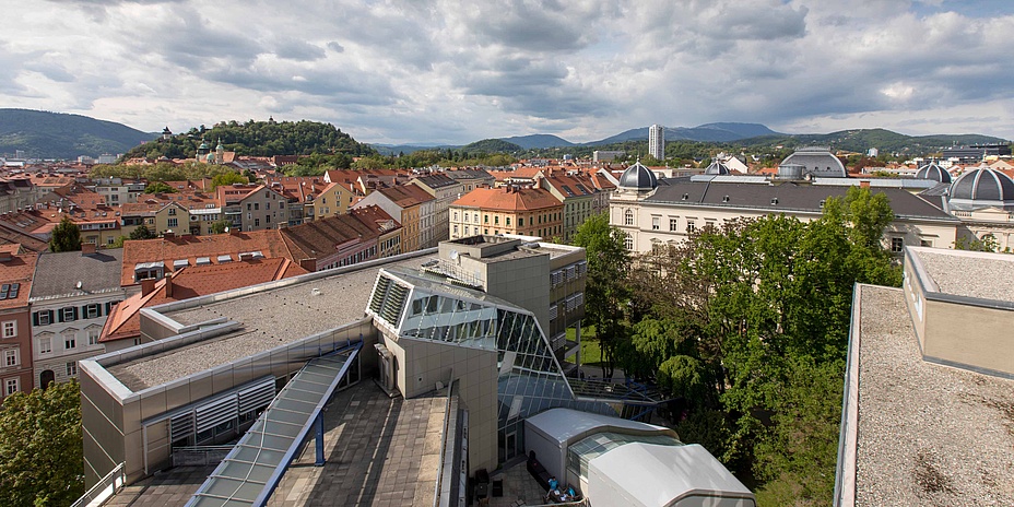 Blick von oben auf moderne Dachlandschaft vorne und historische Dachlandschaft im Hintergrund