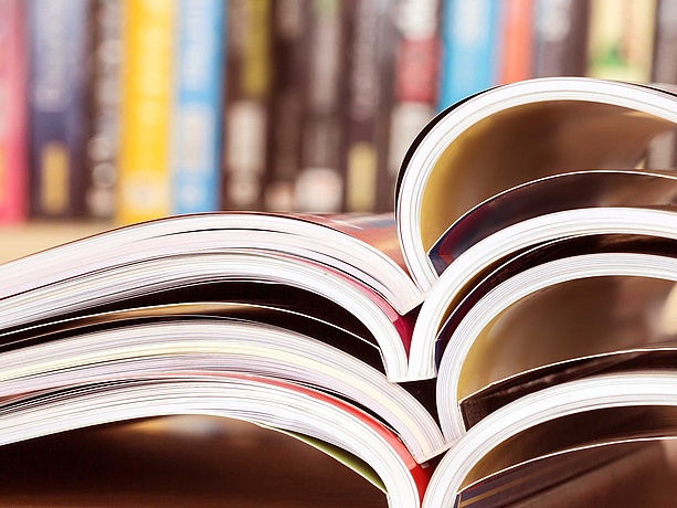 Aufgeschlagene Hefte vor einem Regal