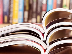 Aufgeschlagene Hefte vor einem Regal