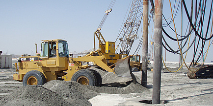 Eine große Baumaschine nimmt Bohrungen im Wüstensand vor.