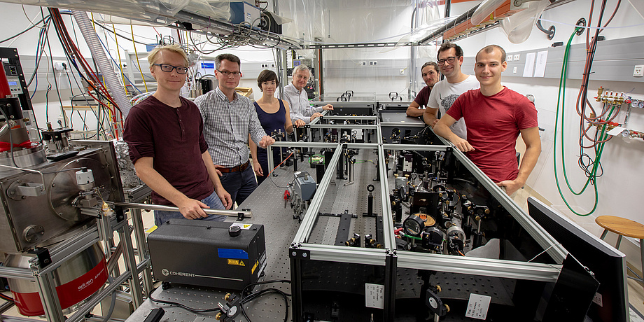 A group of researchers in the physics laboratory standing around a femtosecond laser