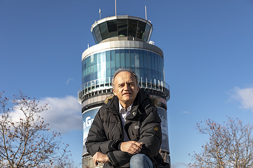 Smiling man in front of a glazed tower.