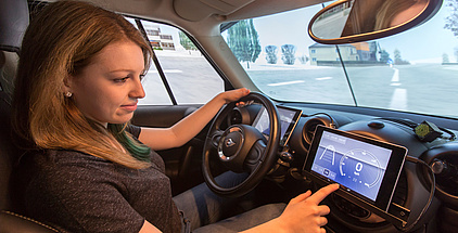 Frau am Steuer eines Autos bedient ein Navigationssystem im Cockpit