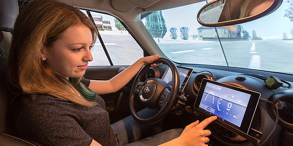 Woman behind the wheel of a car operating a navigation system in the cockpit