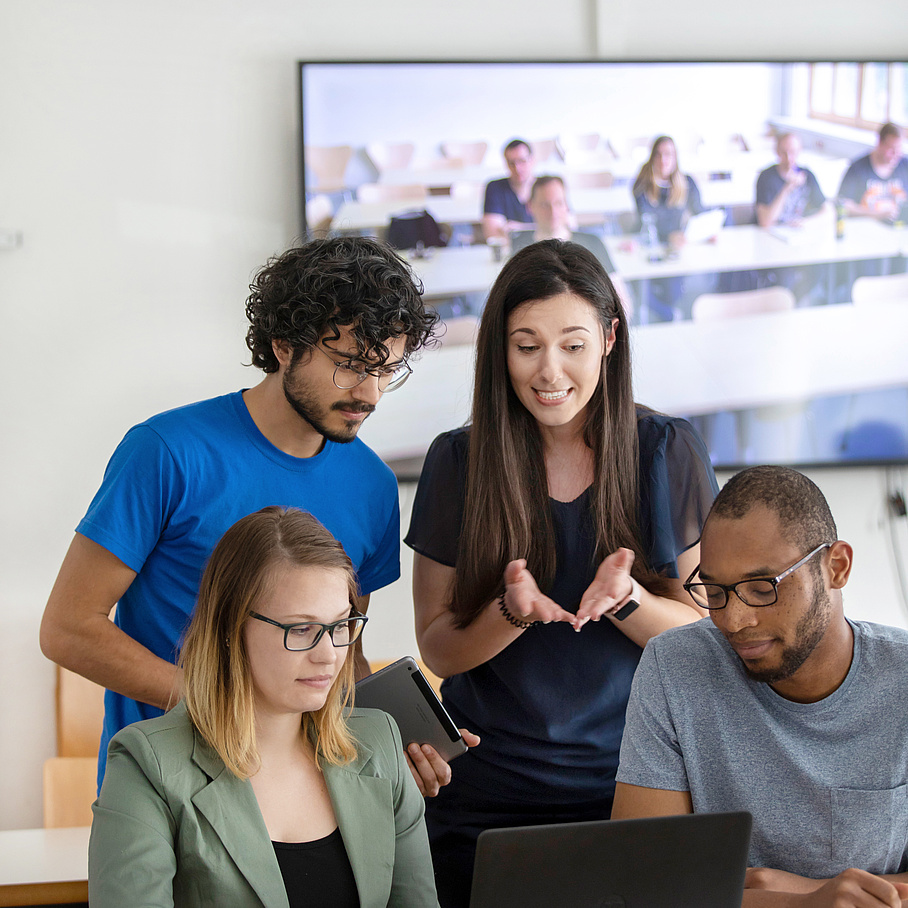 Zwei Frauen und zwei Männer im Gespräch, dahinter eine große Videowall.