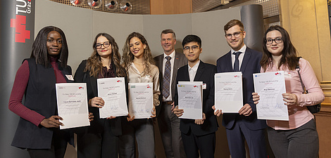 Seven people are standing next to each other, holding certificates in their hands and looking at the camera.