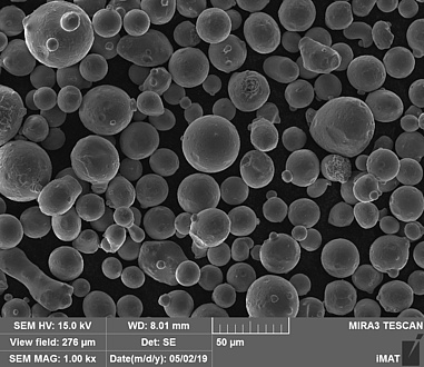 Mikroskop-Aufnahme des neuen Pulvers, viele graie Bälle auf schwarzen Hintergrund, darunter sind Daten zur Mikroskopeinstellung abzulesen