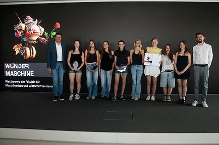 Ten people stand next to each other on a stage and smile into the camera.